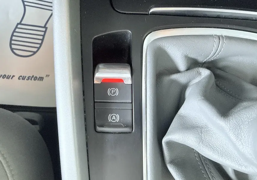 Gros plan sur la commande de frein à main électronique et le soufflet de levier de vitesse en cuir gris dans un Audi Q5 noir.
