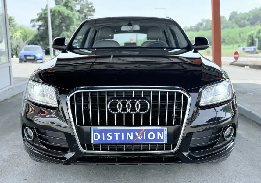 Vue frontale d'un Audi Q5 noir avec calandre chromée et phares allumés, sous un abri extérieur.