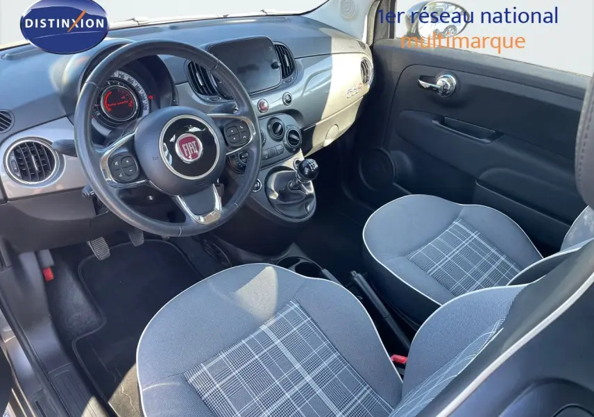 Intérieur clair de la Fiat 500C 2019, vue côté conducteur, avec tableau de bord gris métallisé et sièges tissu gris à motifs.