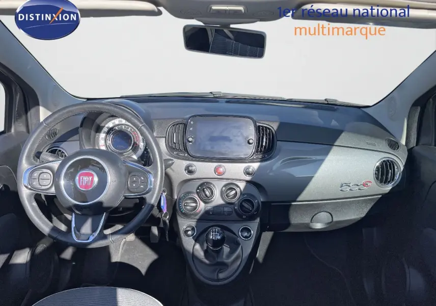 Intérieur avant de la Fiat 500C grise, tableau de bord avec volant, commandes manuelles et écran central tactile.