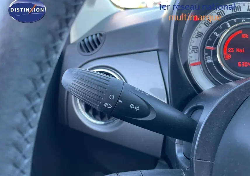 Gros plan sur la commande des clignotants et le tableau de bord gris d'une Fiat 500C 2019 vue côté gauche.
