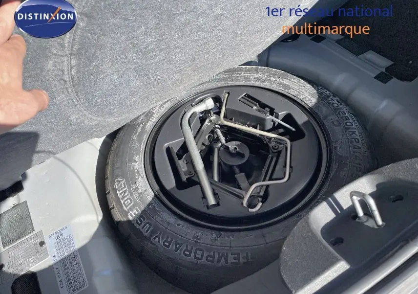 Gros plan sur la roue de secours et les outils de bord dans le coffre d'une Fiat 500C gris électroclash.