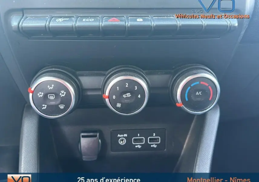Gros plan sur les commandes de climatisation manuelle et les ports USB d'une Renault Clio V TCe 90 bleu foncé de 2023.