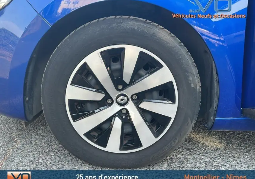 Gros plan sur la roue avant gauche d'une Renault Clio bleu foncé 2023 avec jante alliage au design moderne.