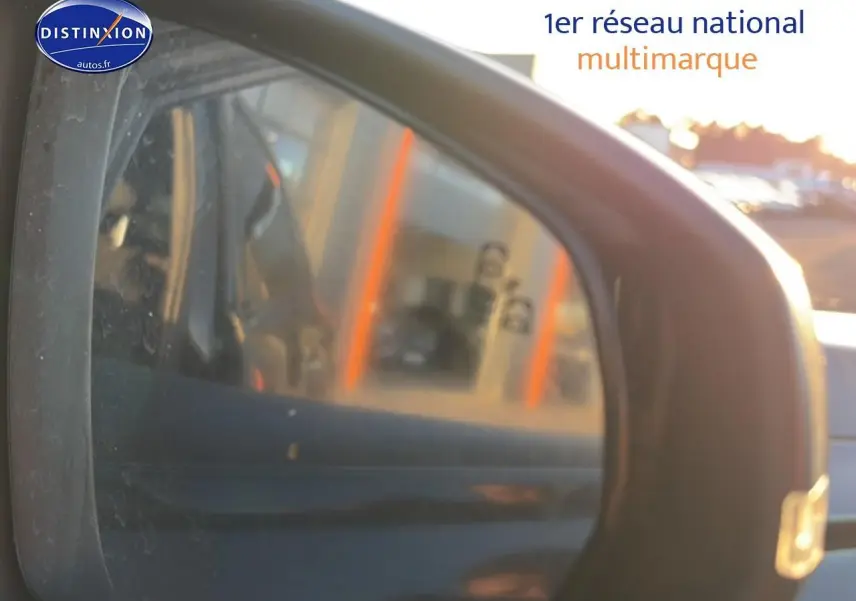 Rétroviseur extérieur droit d’un DS7 noir, avec reflet flou d’un bâtiment et lumière du soleil en arrière-plan.