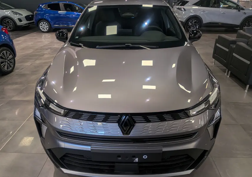 Vue avant rapprochée de la Renault SYMBIOZ E-TECH gris Cassiopé, mettant en valeur sa calandre moderne et ses phares fins.