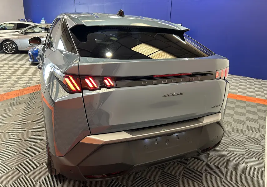 Vue 3/4 arrière droite du Peugeot 3008 Hybrid bleu Ingaro avec feux arrière allumés dans un showroom.