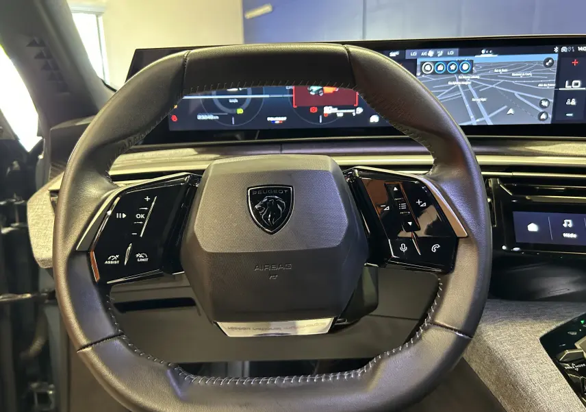 Vue rapprochée du volant cuir noir du Peugeot 3008 Hybrid 2024 avec tableau de bord numérique et écran tactile panoramique.