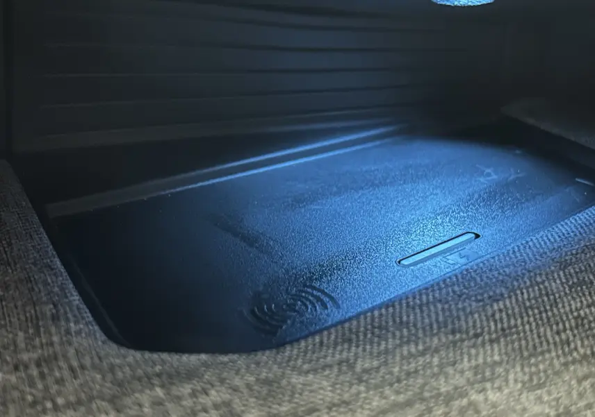 Gros plan sur le chargeur à induction intégré dans l'accoudoir central du Peugeot 3008 Hybrid 2024.