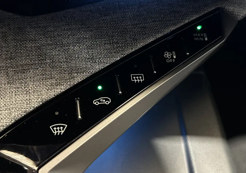 Gros plan sur les commandes de climatisation et désembuage du Peugeot 3008 III Hybrid, avec éclairage vert des voyants.