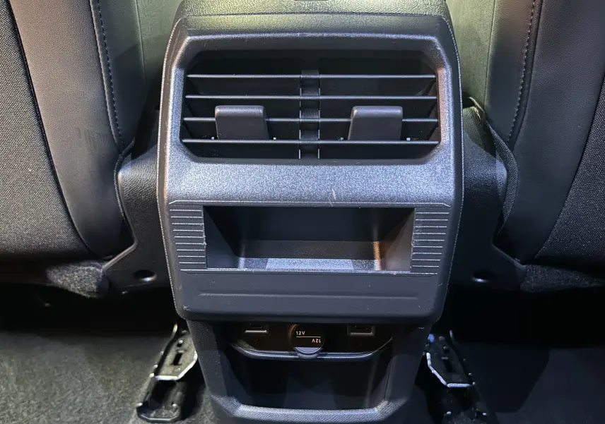 Vue rapprochée de la console arrière noire avec bouches d’aération et prises USB du Peugeot 3008 Hybrid 2024.
