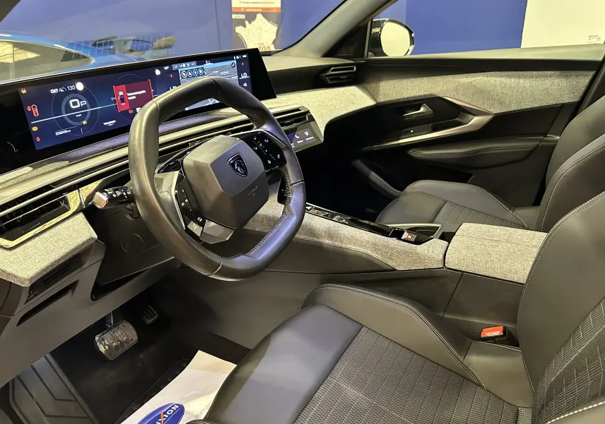 Vue intérieure côté conducteur du Peugeot 3008 Hybrid 2024 avec tableau de bord numérique et sellerie cuir gris.