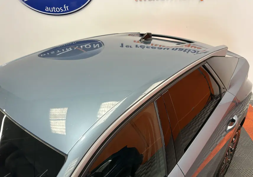 Vue plongeante sur le toit panoramique et la partie droite d’un Peugeot 3008 bleu Ingaro en intérieur showroom.