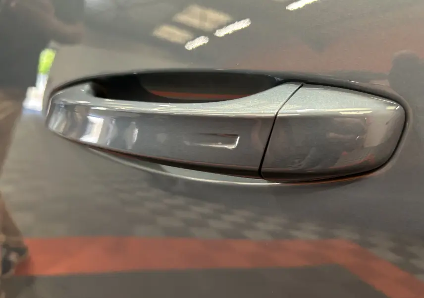 Poignée de porte côté gauche du Peugeot 3008 III Hybrid 136 e-DCS6 Allure en bleu Ingaro, vue en gros plan.