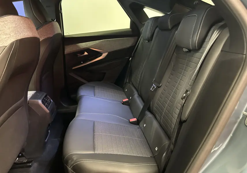 Vue intérieure côté droit des sièges arrière en cuir noir du Peugeot 3008 Hybrid 2024, avec surpiqûres contrastantes.