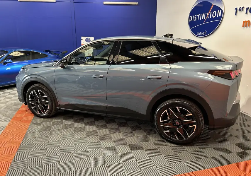 Vue de profil droit du Peugeot 3008 III Hybrid 136 bleu Ingaro avec jantes noires et toit panoramique en intérieur showroom.