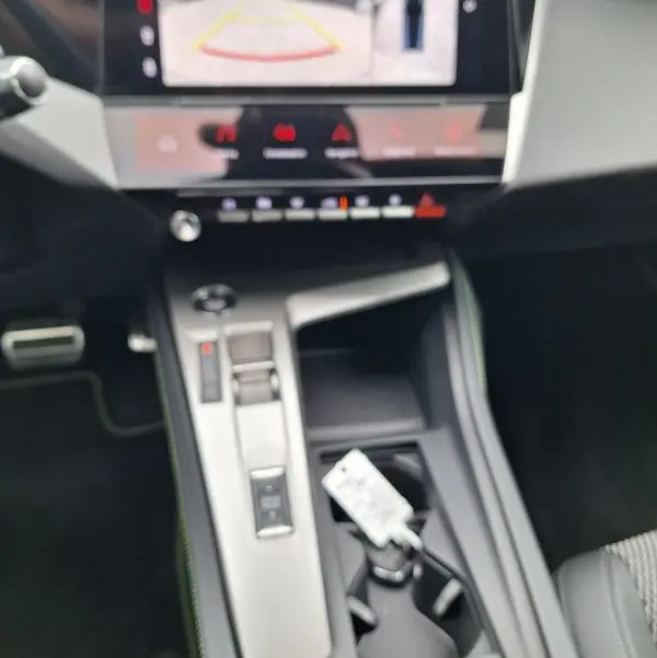 Vue intérieure centrée sur la console centrale et l'écran tactile affichant la caméra de recul du Peugeot 308 Hybrid gris.