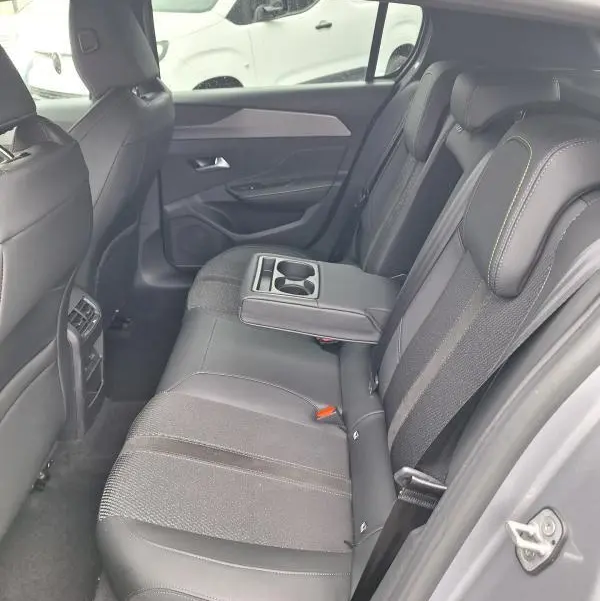 Vue intérieure côté droit des sièges arrière gris du Peugeot 308 Hybrid 145 e-DCS6 GT avec accoudoir central et porte-gobelets.