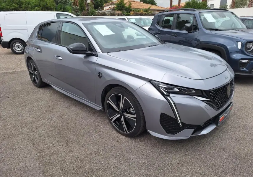 Peugeot 308 Hybrid gris vue 3/4 avant droit, jantes alliage 18 pouces et signature lumineuse LED distinctive.