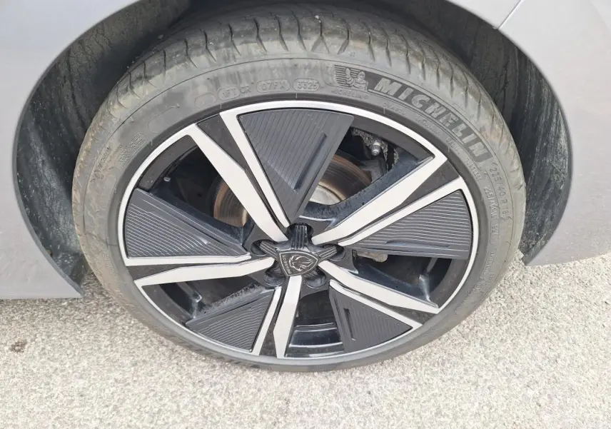 Gros plan sur la jante alliage 18 pouces noire et argentée d'une Peugeot 308 Hybrid 145 e-DCS6 GT gris.