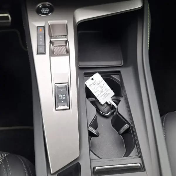 Vue rapprochée de la console centrale grise de la Peugeot 308 Hybrid 145 e-DCS6 GT avec levier de vitesses automatique et porte-gobelets.