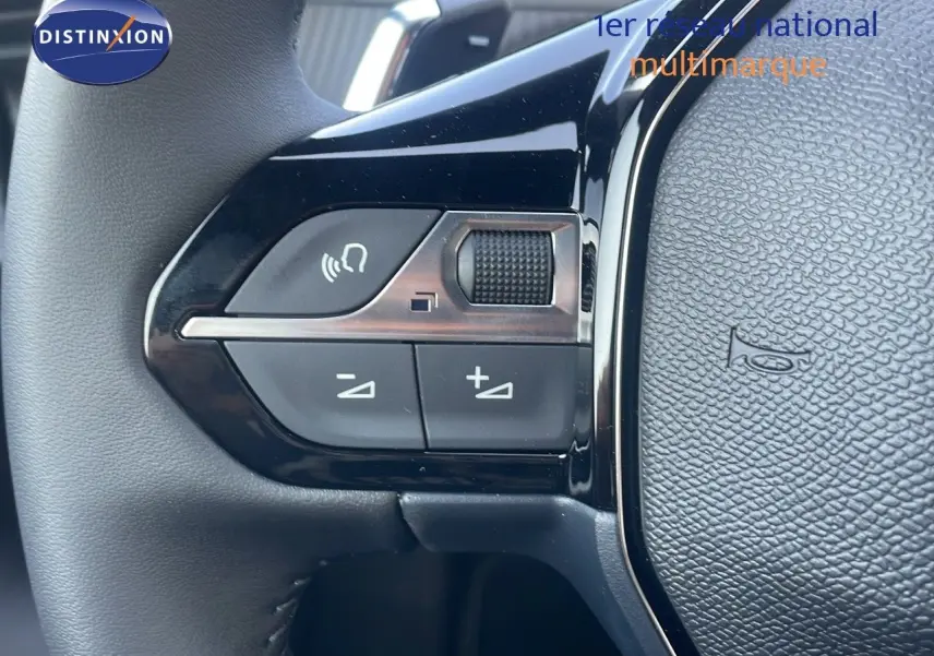 Gros plan sur les commandes au volant du Peugeot 2008 gris Artense, mettant en valeur les boutons de réglage sonore.