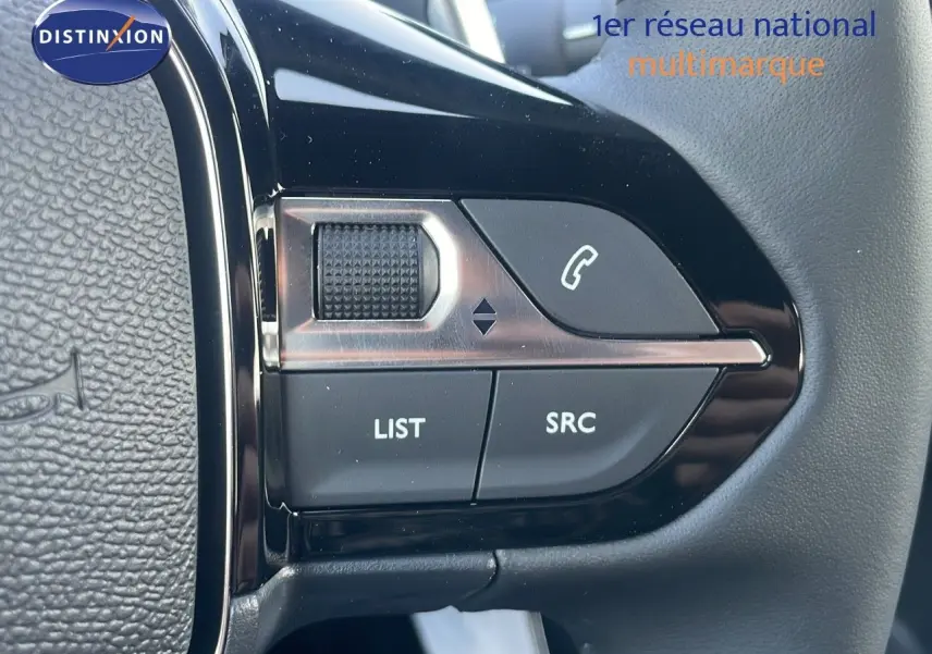 Gros plan sur les commandes gauche du volant du Peugeot 2008 Hybrid gris Artense, boutons LIST, SRC et téléphone.
