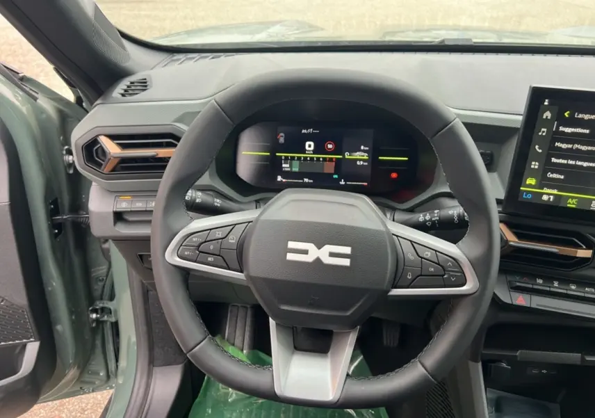 Vue intérieure centrée sur le volant du Dacia Duster 2025 kaki lichen, avec tableau de bord numérique et écran tactile visible.