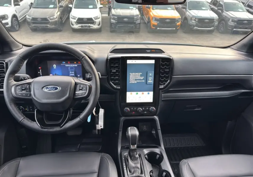 Vue intérieure du Ford Ranger 2025 montrant le tableau de bord noir avec écran tactile vertical et volant multifonctions.