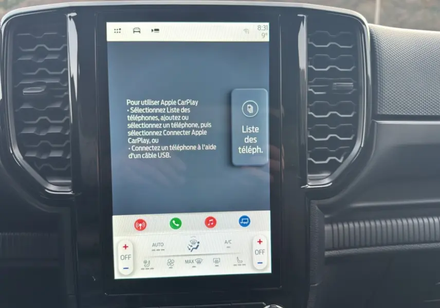 Écran tactile central du Ford Ranger blanc glacier 2025 affichant les instructions Apple CarPlay, entouré de grilles d'aération noires.