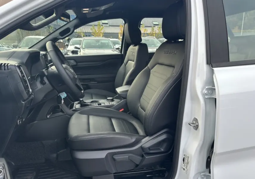 Vue intérieure côté conducteur du Ford Ranger Tremor blanc glacier, avec sièges en cuir noirs marqués Tremor.