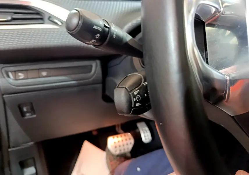 Gros plan sur le volant cuir et les commandes de régulateur de vitesse du Peugeot 2008 gris foncé, intérieur conducteur.