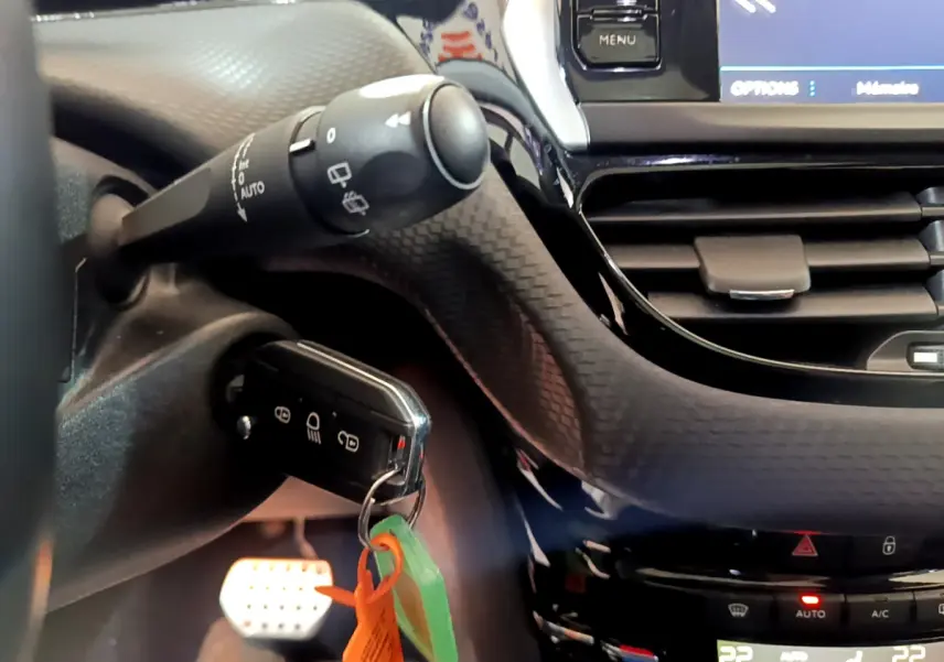 Gros plan sur le tableau de bord et la clé insérée du Peugeot 2008 gris foncé, avec commandes et écran tactile visibles.