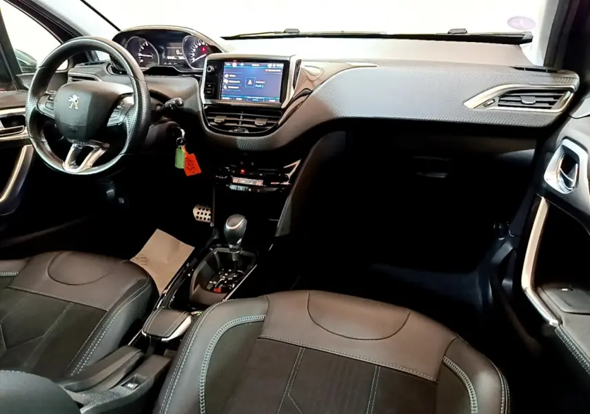 Intérieur du Peugeot 2008 gris foncé, vue de face montrant le tableau de bord avec écran tactile et volant cuir multifonctions.