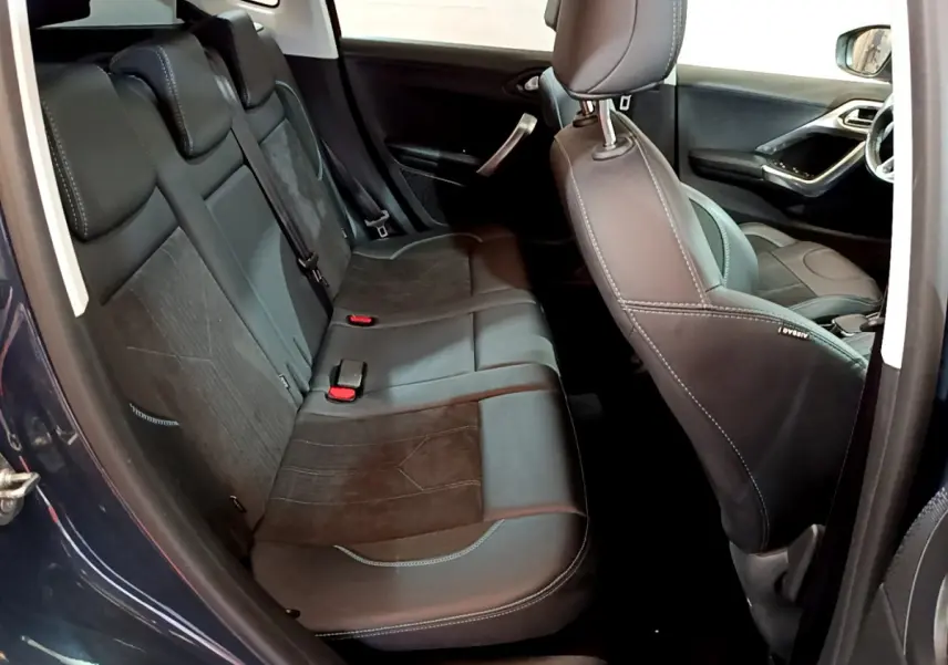 Vue intérieure côté gauche montrant la banquette arrière et le siège avant en cuir noir du Peugeot 2008 gris foncé.