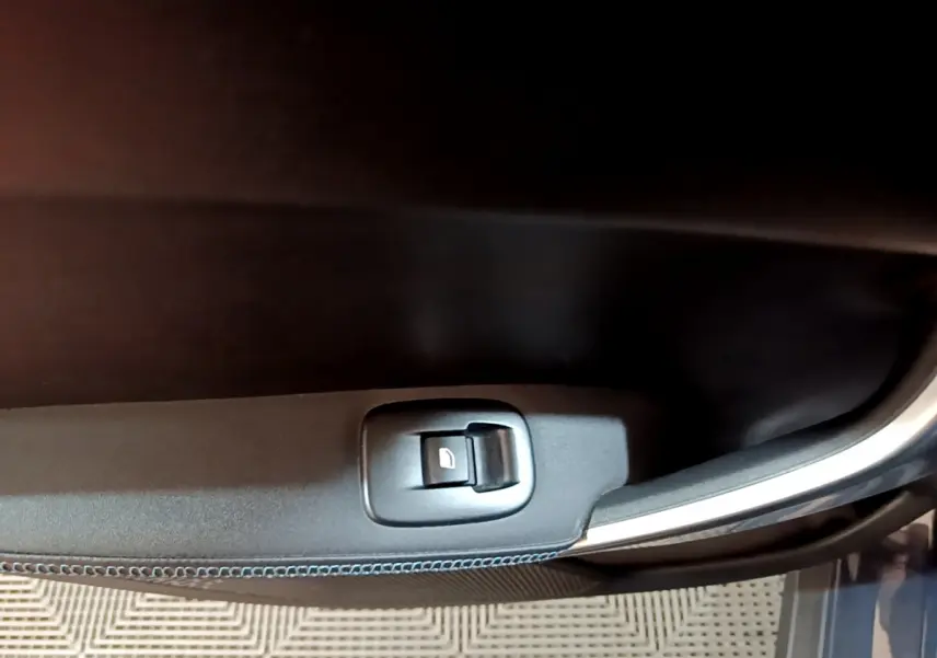 Bouton de commande de vitre électrique sur la porte côté gauche d'un Peugeot 2008 gris foncé, version Crossway.