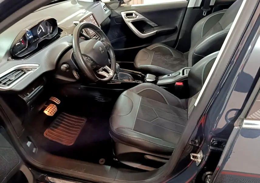 Intérieur du Peugeot 2008 gris foncé vu côté conducteur, avec sièges cuir et tableau de bord moderne tactile.