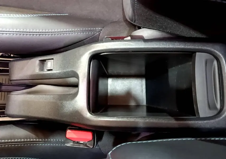 Vue plongeante sur le rangement central noir entre les sièges avant du Peugeot 2008 gris foncé de 2019.