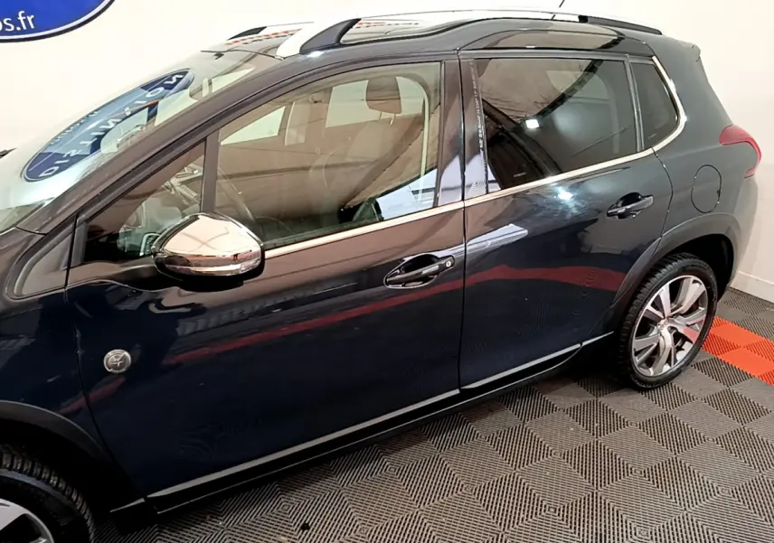 Profil côté gauche d'un Peugeot 2008 gris foncé avec rétroviseurs chromés et jantes alliage visibles.