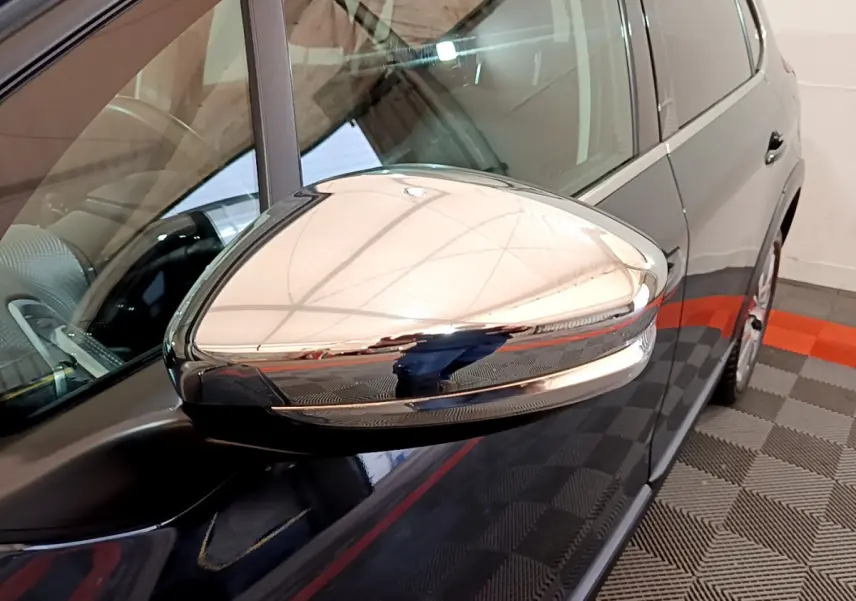 Rétroviseur chromé en gros plan côté gauche d'un Peugeot 2008 gris foncé, vue partielle du véhicule stationné.