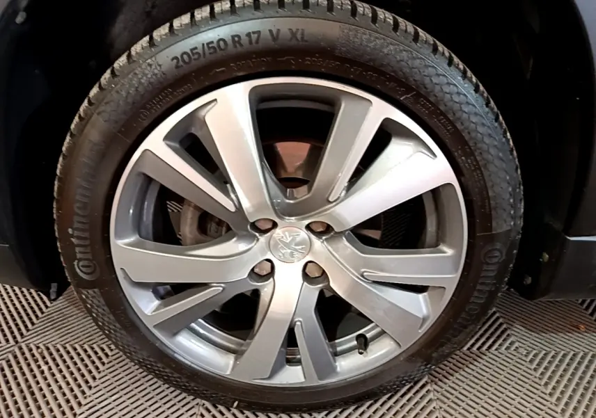 Gros plan sur la jante alliage argentée et pneu Continental du côté avant droit d'un Peugeot 2008 gris foncé.