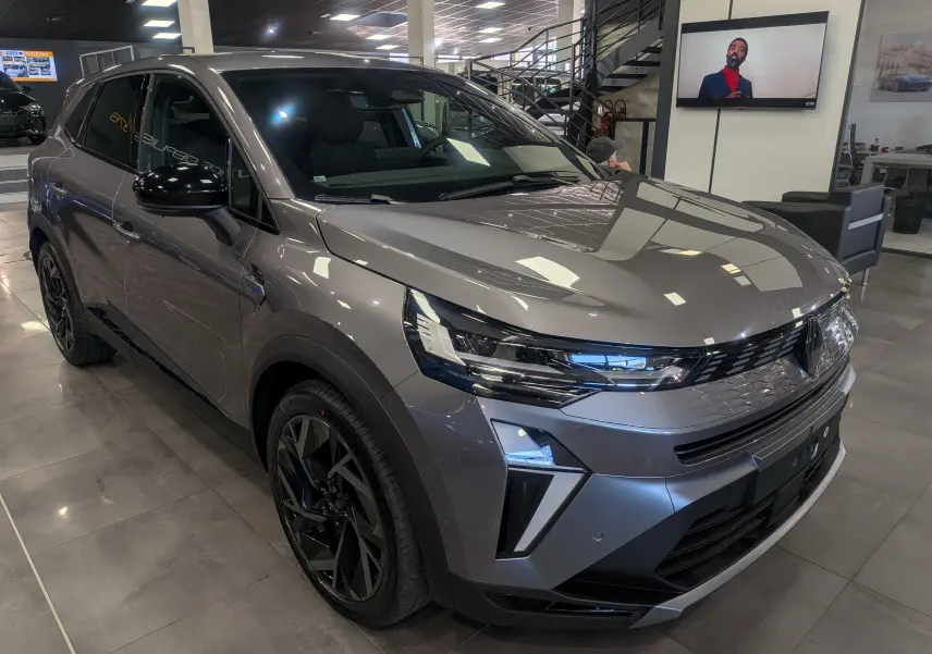 Renault Symbioz E-Tech gris Cassiopé en 3/4 avant droit, avec jantes noires et éclairage LED distinctif.