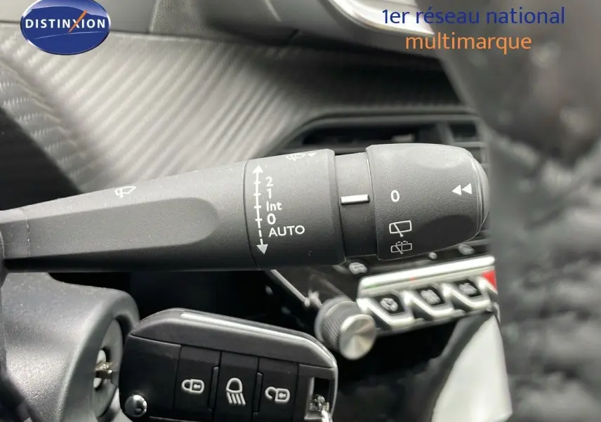 Gros plan sur la commande d'essuie-glace et la clé de contact dans l'habitacle d'une Peugeot 208 noire.