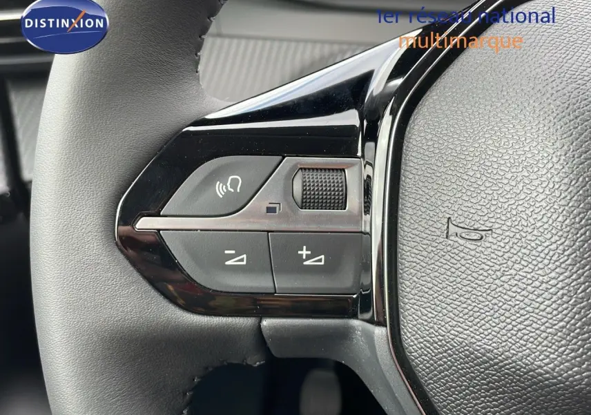 Gros plan sur les commandes du volant de la Peugeot 208 noire, mettant en valeur les boutons de volume et de téléphone.