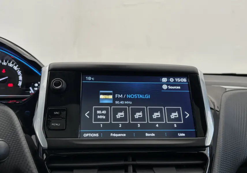 Vue rapprochée de l'écran tactile multimédia du Peugeot 2008 rouge, affichant la radio FM sur fond noir et bleu.