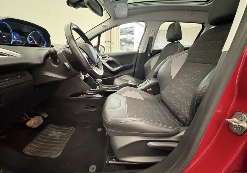 Intérieur avant droit d'une Peugeot 2008 rouge 2019, sièges en cuir noir et gris, volant multifonctions et toit panoramique visible.