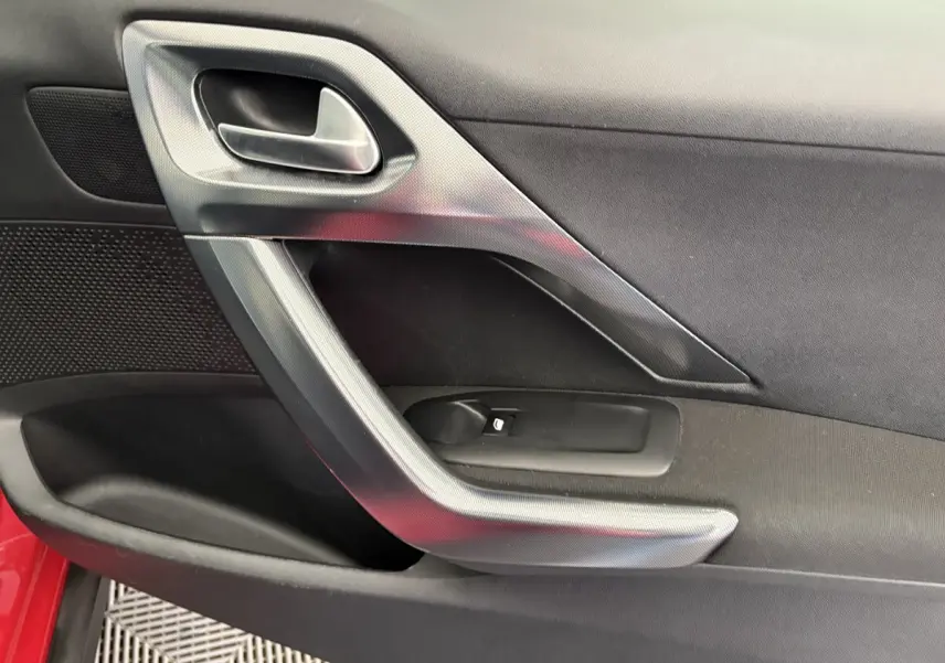 Poignée intérieure côté gauche de la porte avant d'un Peugeot 2008 rouge, finition Allure 2019.