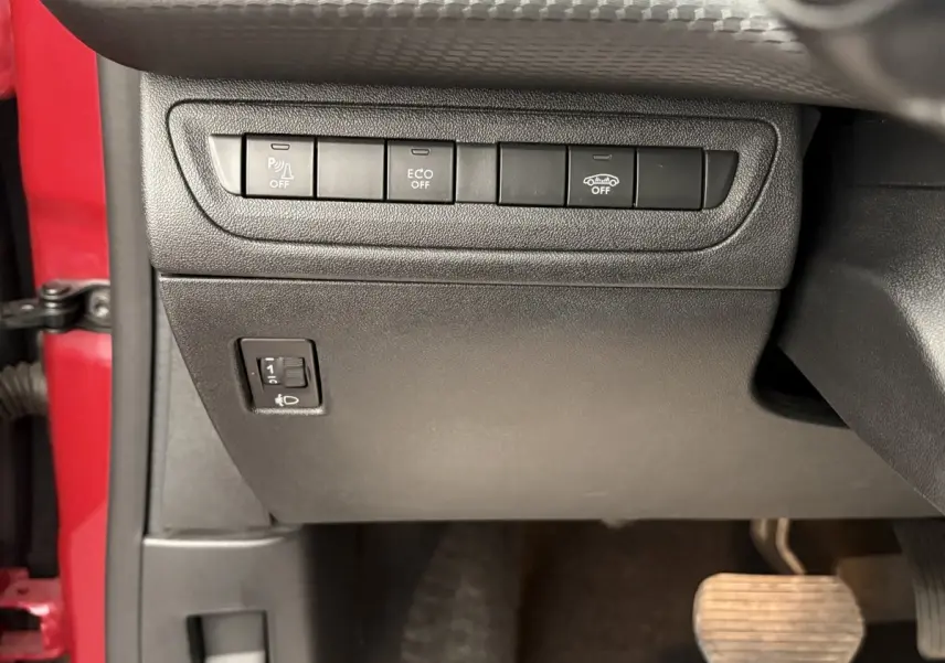 Détail intérieur côté gauche du tableau de bord noir avec boutons de contrôle et portière rouge visible Peugeot 2008 2019.
