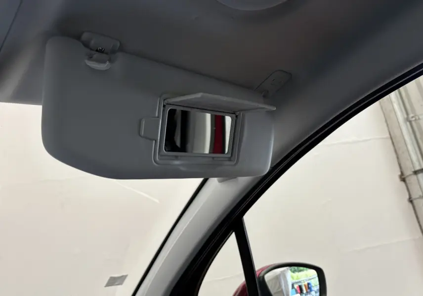 Miroir de courtoisie ouvert sur le pare-soleil côté conducteur dans le Peugeot 2008 rouge, vue intérieure avant droite.