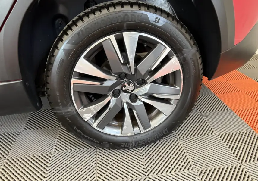 Gros plan sur la roue avant gauche du Peugeot 2008 rouge, avec jante alliage et pneu Bridgestone.